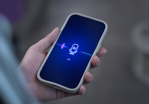 Eine Hand hält ein Smartphone, darauf ist das Logo eines KI-Tools, das gerade eine Sprachaufnahme verarbeitet.